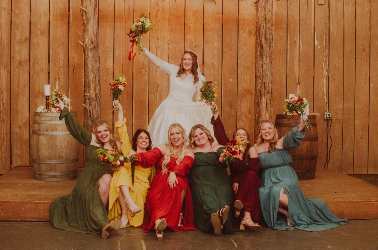 A joyful wedding party celebrating outside a wooden venue