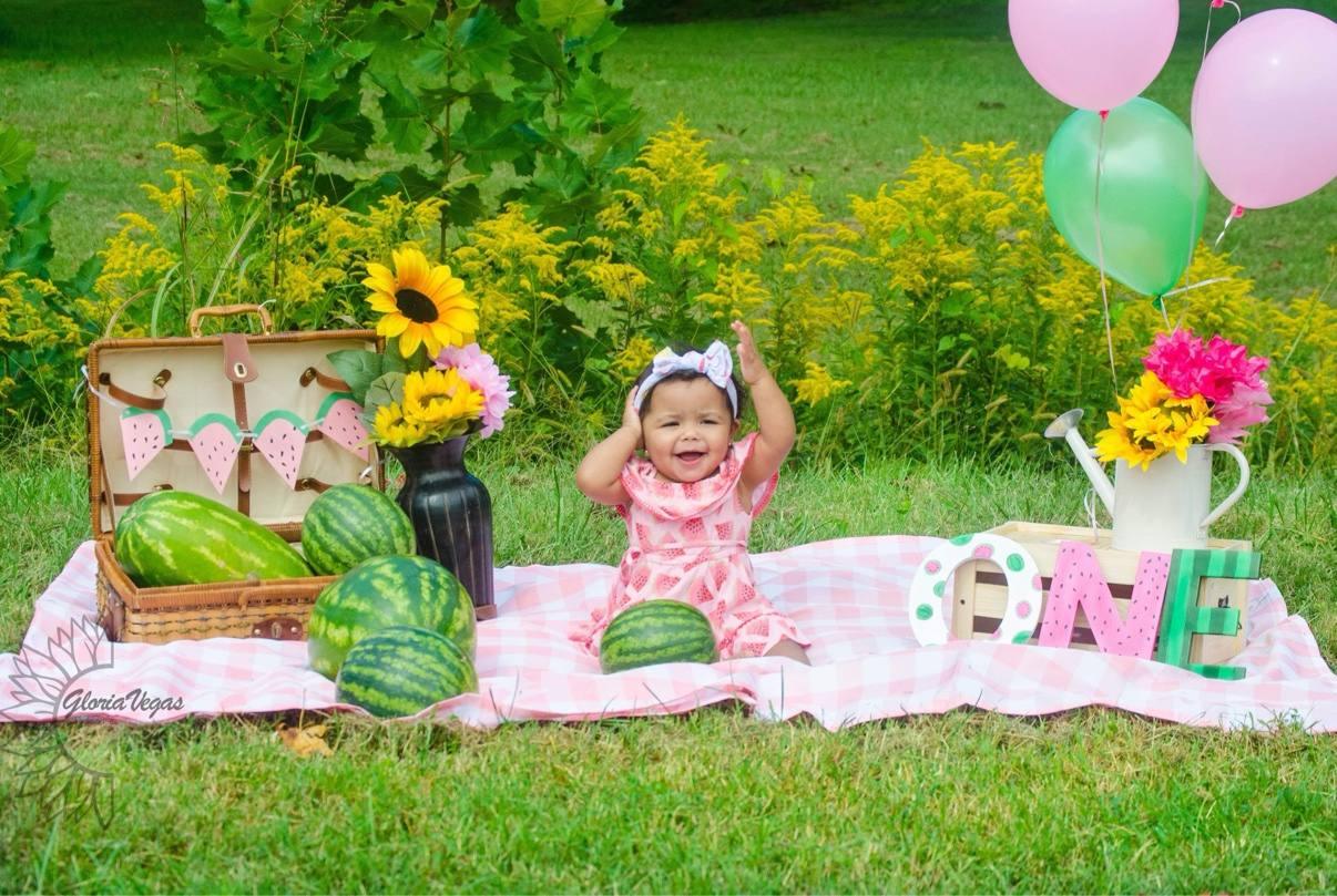 A smiling child at a colorful watermelon-themed first birthday session