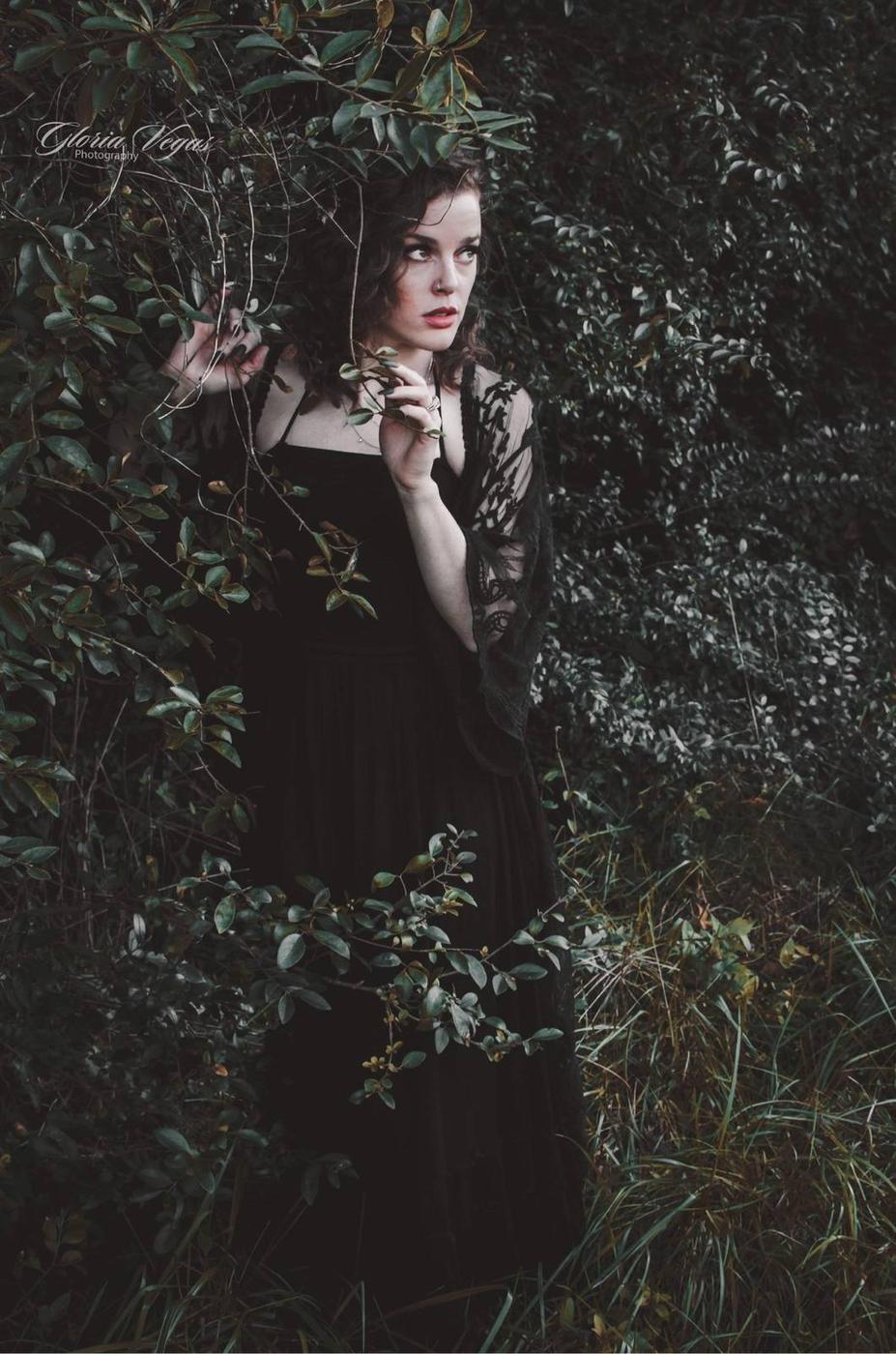 An editorial portrait of a couple among dark greenery