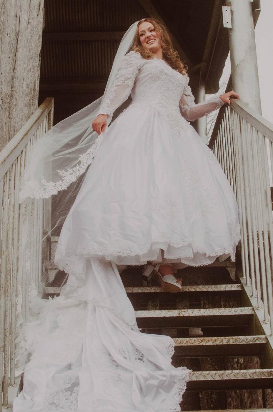A bride descending an outdoor staircase in her wedding gown