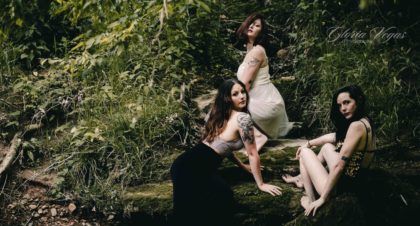 Three friends posed among moss and greenery in a moody forest portrait