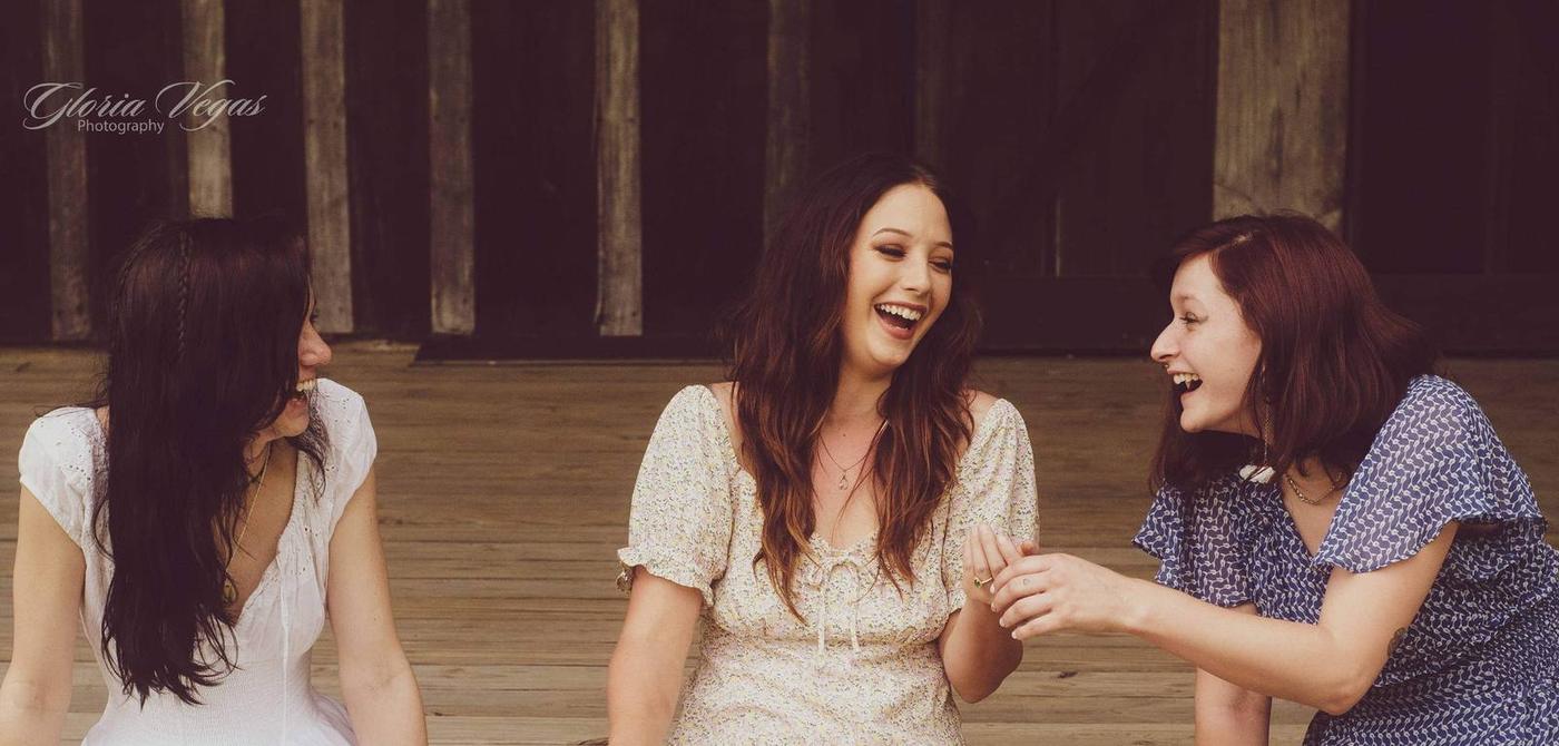 A close portrait of three friends sharing a laugh on a porch