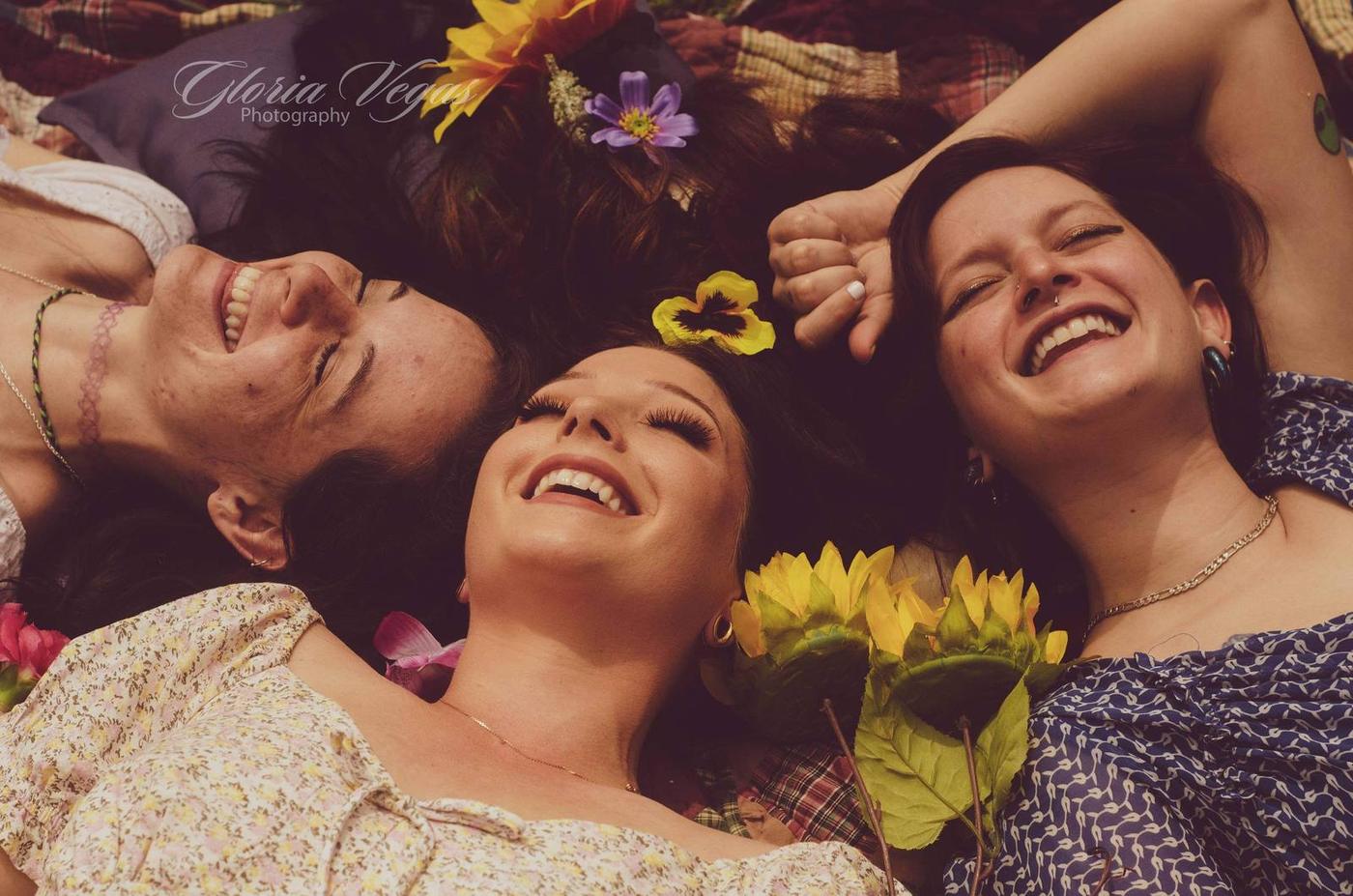 Three friends lying among colorful flowers and laughing together