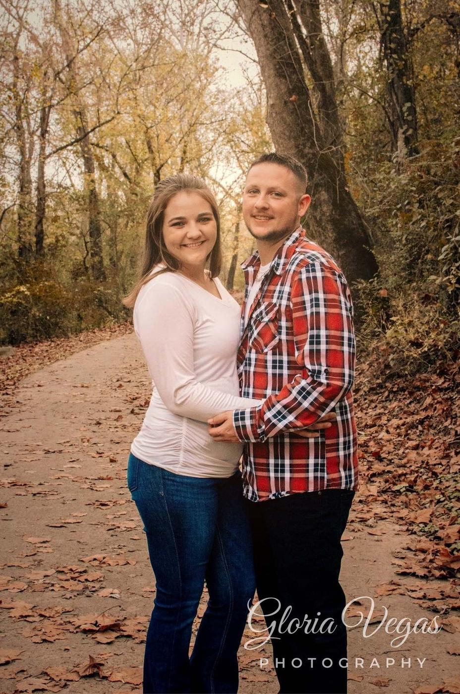 A couple standing together on a leaf-covered woodland path in fall