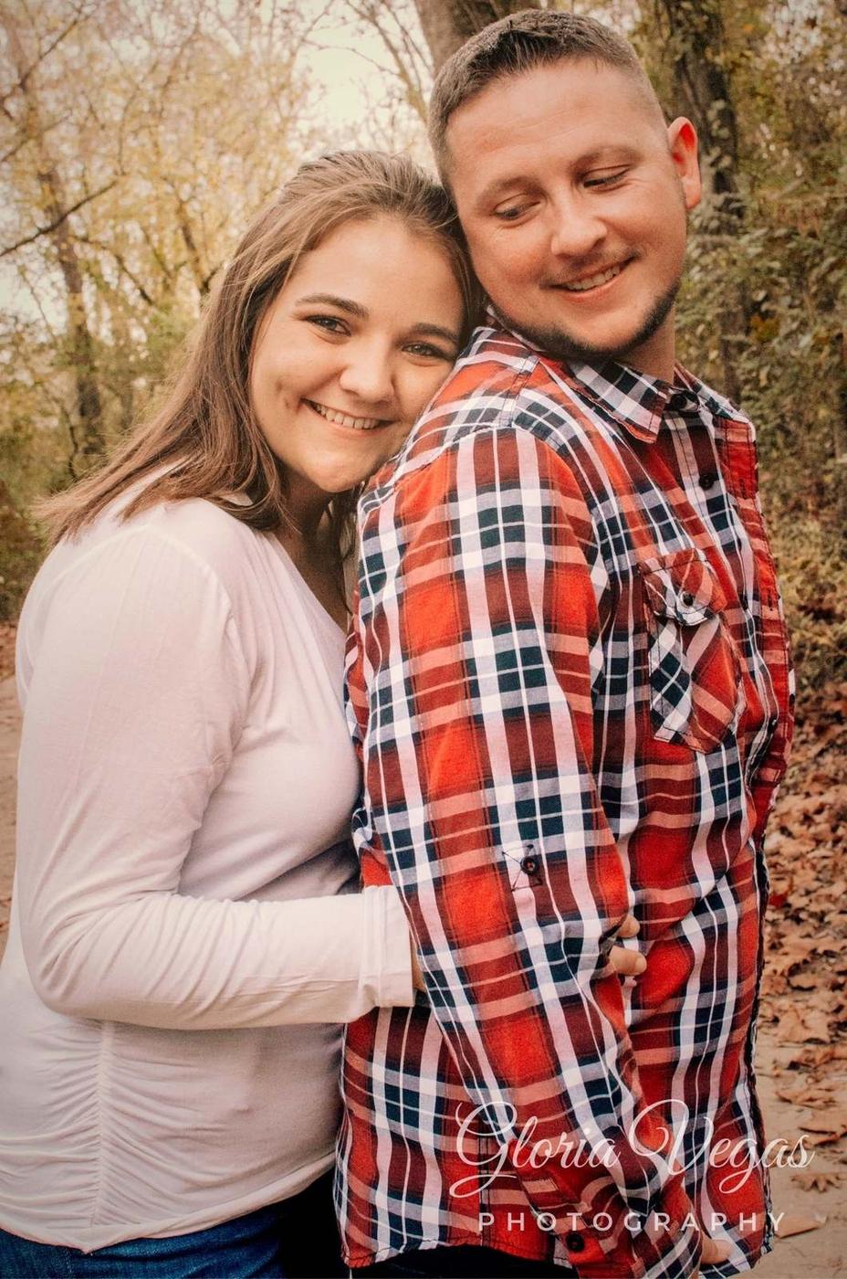 A smiling couple embracing closely outdoors in autumn