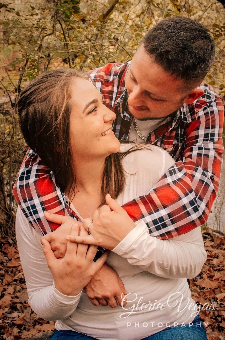 A man embracing a laughing woman from behind in the woods