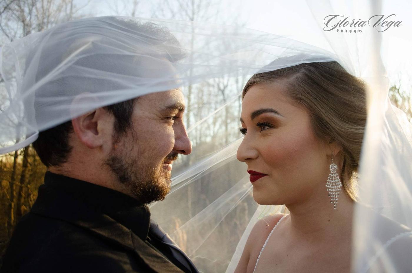 A newlywed couple looking at each other beneath the bride's veil