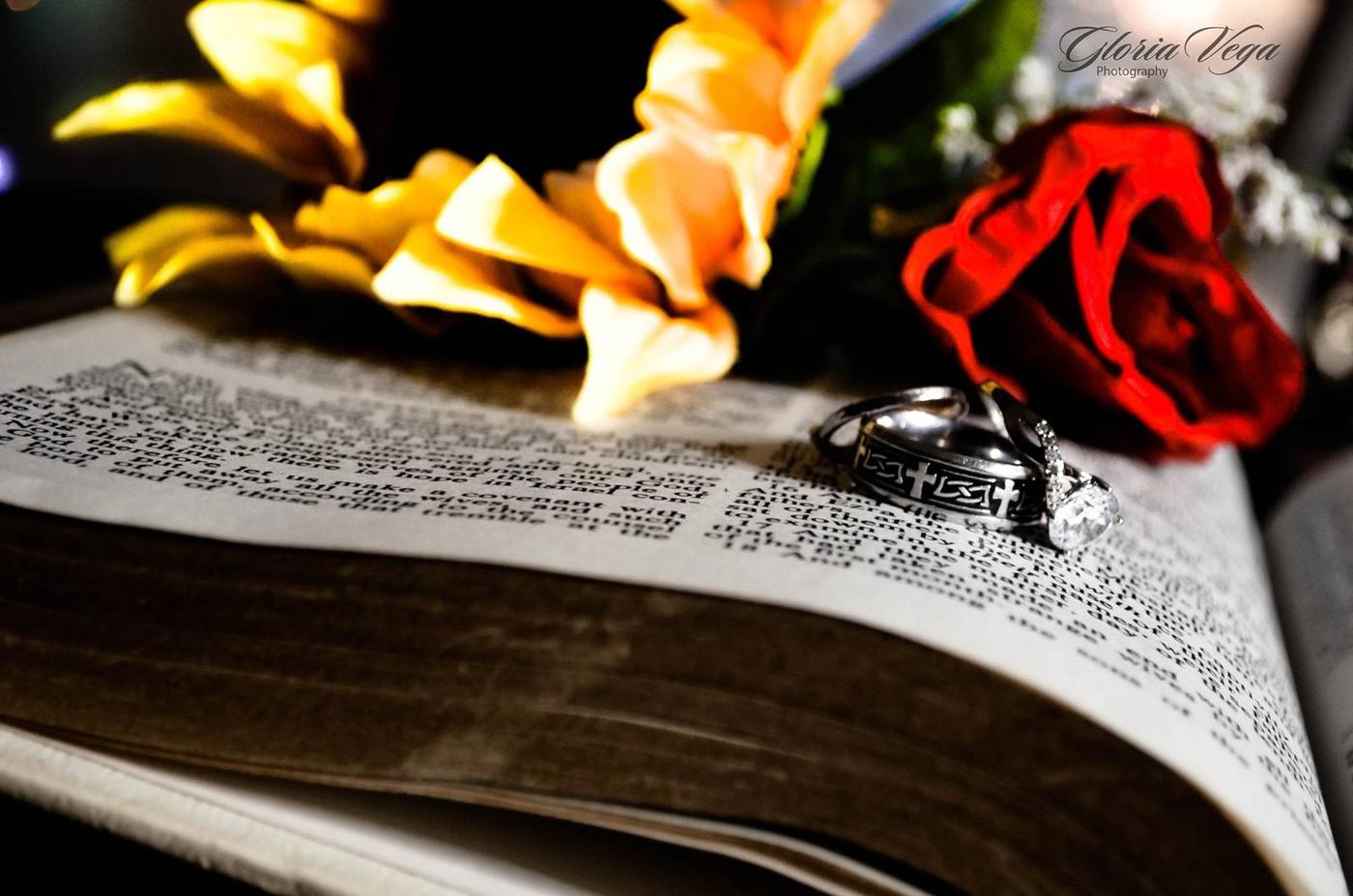 Wedding rings resting on an open Bible beside flowers