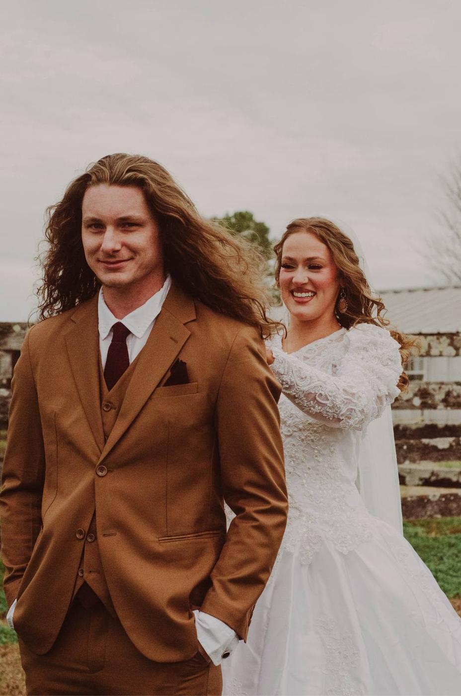 A bride playfully arranging the groom's windblown hair outdoors