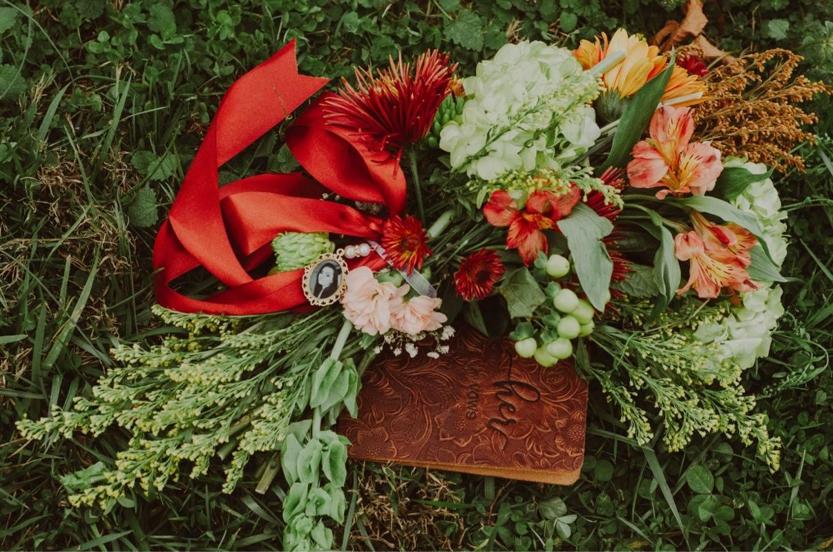 A colorful bridal bouquet and embossed vow book arranged on clover
