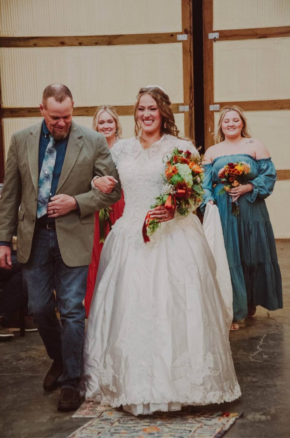 A smiling bride walking down the aisle with her escort and attendants