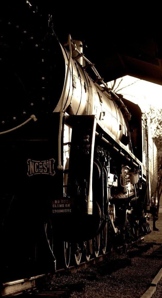 A dramatic low-angle view of a steam locomotive in deep shadow